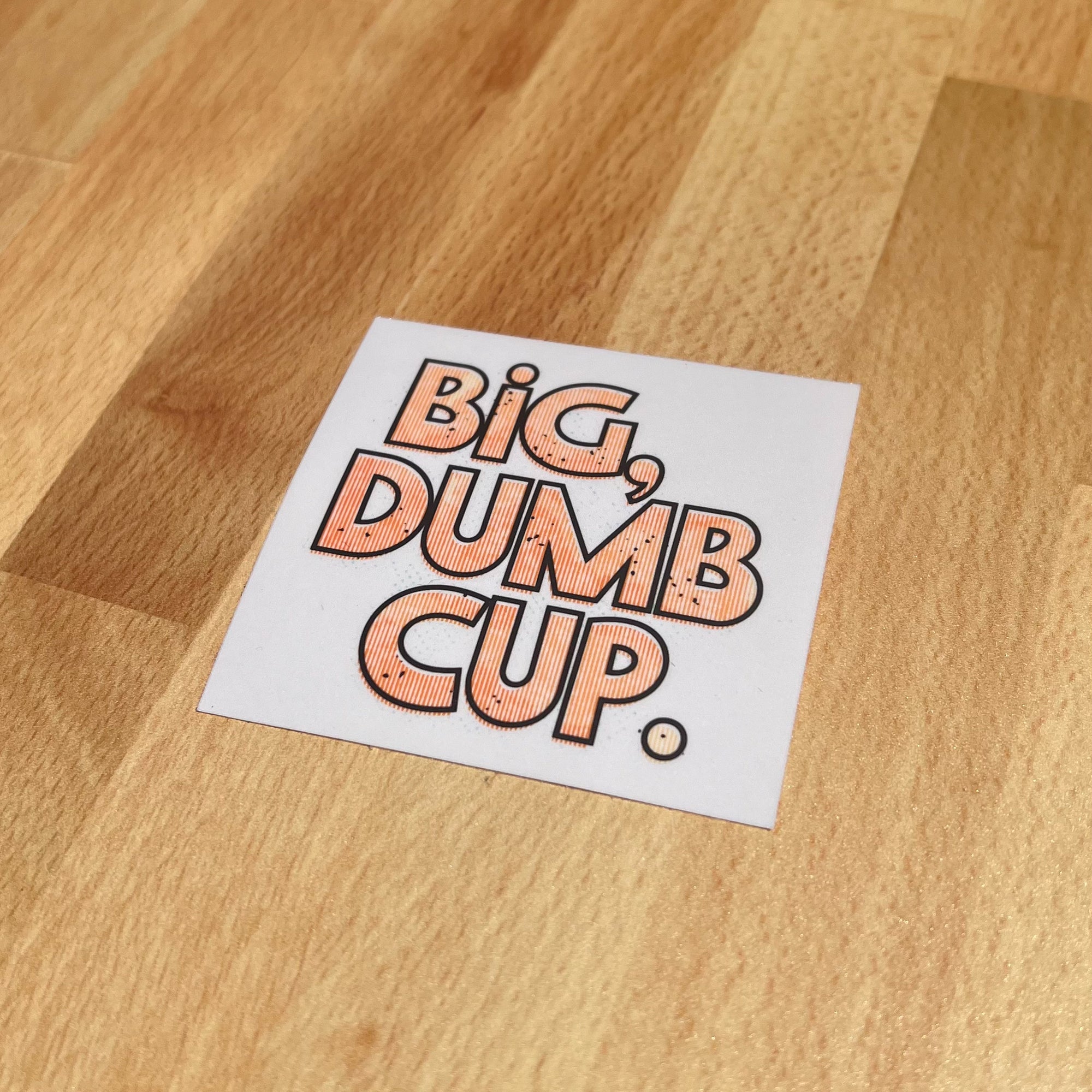 A white, square sticker that reads Big, Dumb Cup on it.