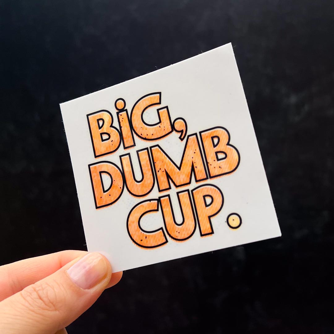 A white, square sticker that reads Big, Dumb Cup on it.