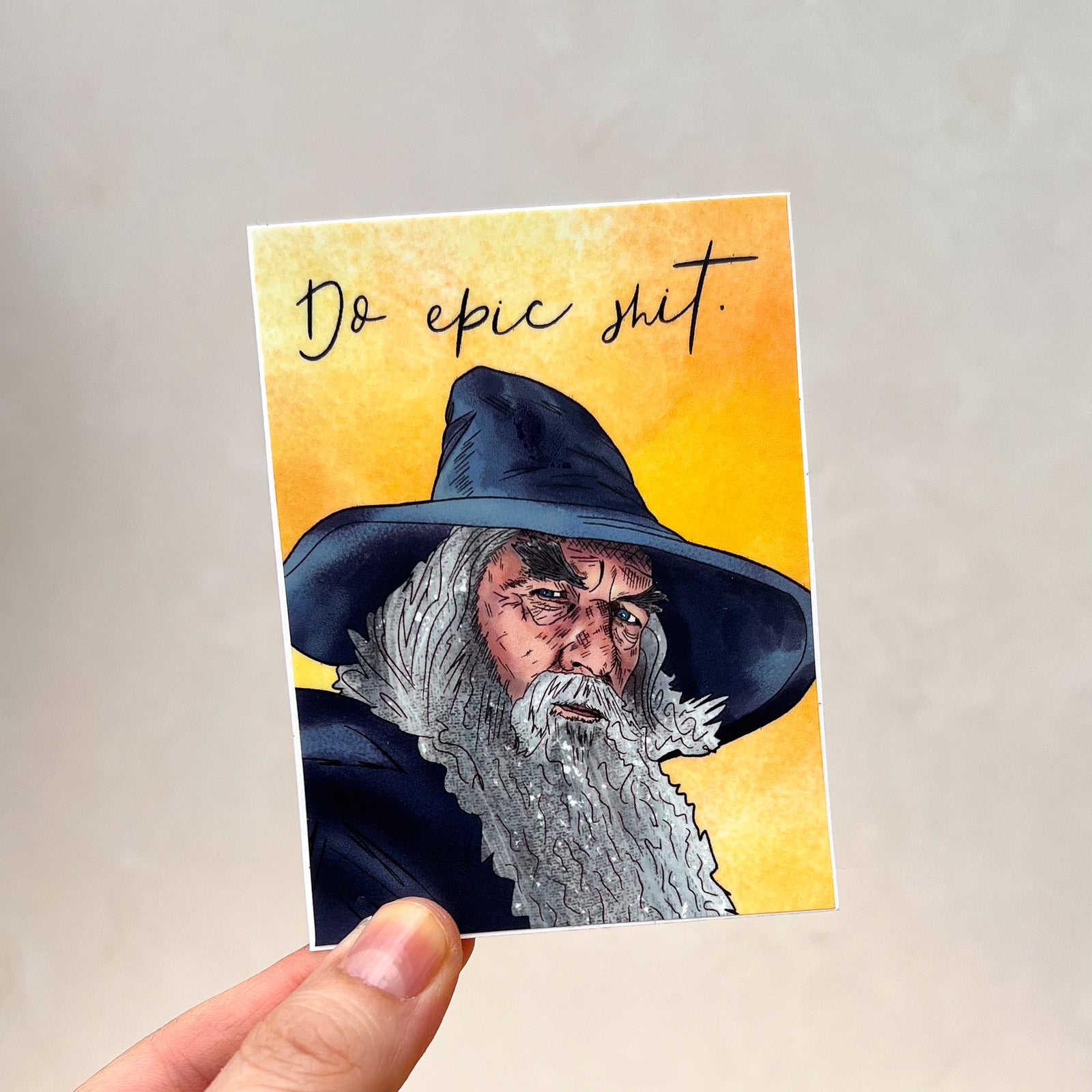 A yellow sticker featuring an illustration of Ian McKellan as Gandalf from all 457 parts of the Lord of the Rings franchise. At the top it says "Do Epic Shit" in a modern cursive typeface.