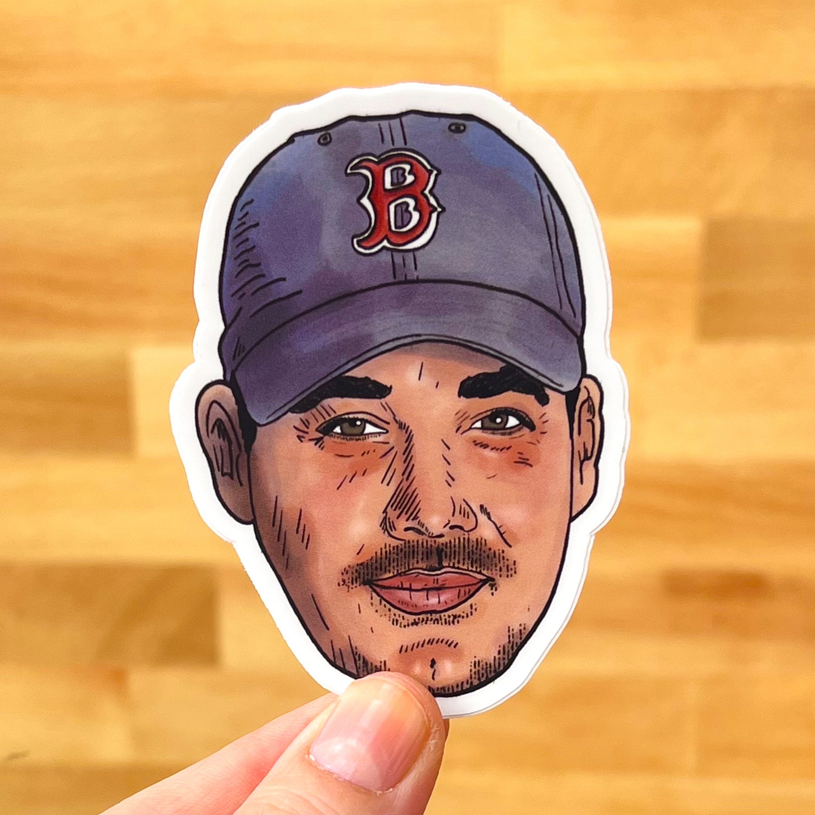 An illustration of Boston Rob from Survivor turned into a rad, 3-inch sticker. In this photo, it's held against a light wood background.